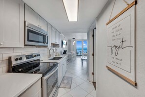 A modern kitchen with stainless steel appliances, white cabinetry, and a view to the outside.