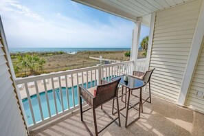 A balcony with a view of the ocean, a pool, and outdoor furniture. - Coastal Beachfront Getaway Poolside and Oceanfront (North Myrtle Beach)