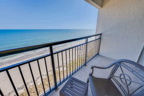 A balcony with a view of the beach and ocean.
