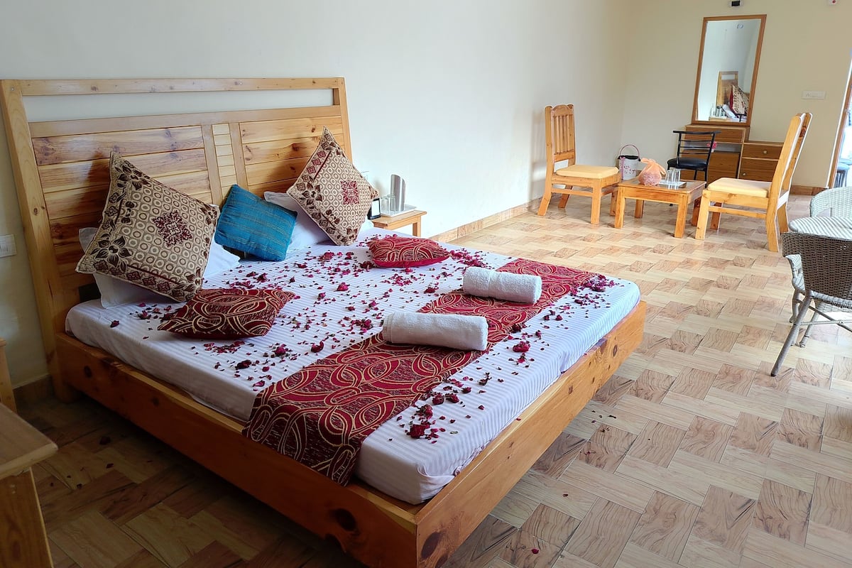 Una cama bien hecha con ropa de cama y almohadas estampadas, un cabecero de madera y piso de madera.