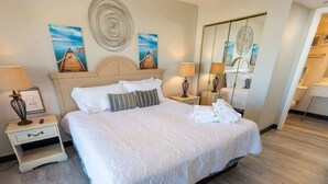 A neatly made bed with white linens and pillows, a bedside table with a lamp, and artwork on the wall. - 3BR in Sand Dunes Resort Ocean View - Great Views (Myrtle Beach)