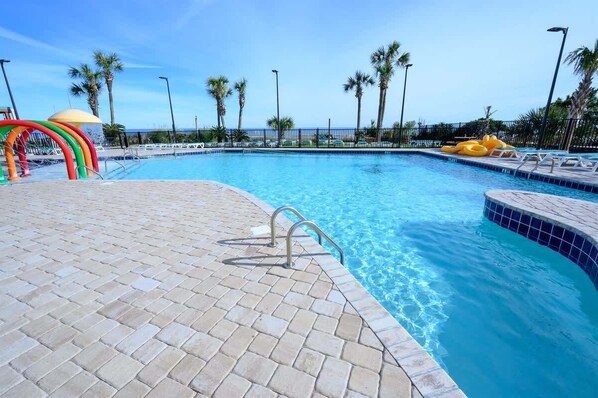 A swimming pool with a tiled deck, a lifeguard stand, and a palm tree-lined view. - 3BR in Sand Dunes Resort Ocean View - Great Views (Myrtle Beach)