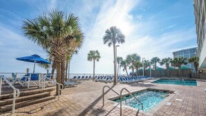 A poolside area with palm trees, lounge chairs, and a swimming pool.