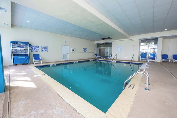 Une piscine intérieure à l’eau d’un bleu limpide, dotée d’un poste de surveillance pour le sauveteur et d’un point de dépôt pour les serviettes.