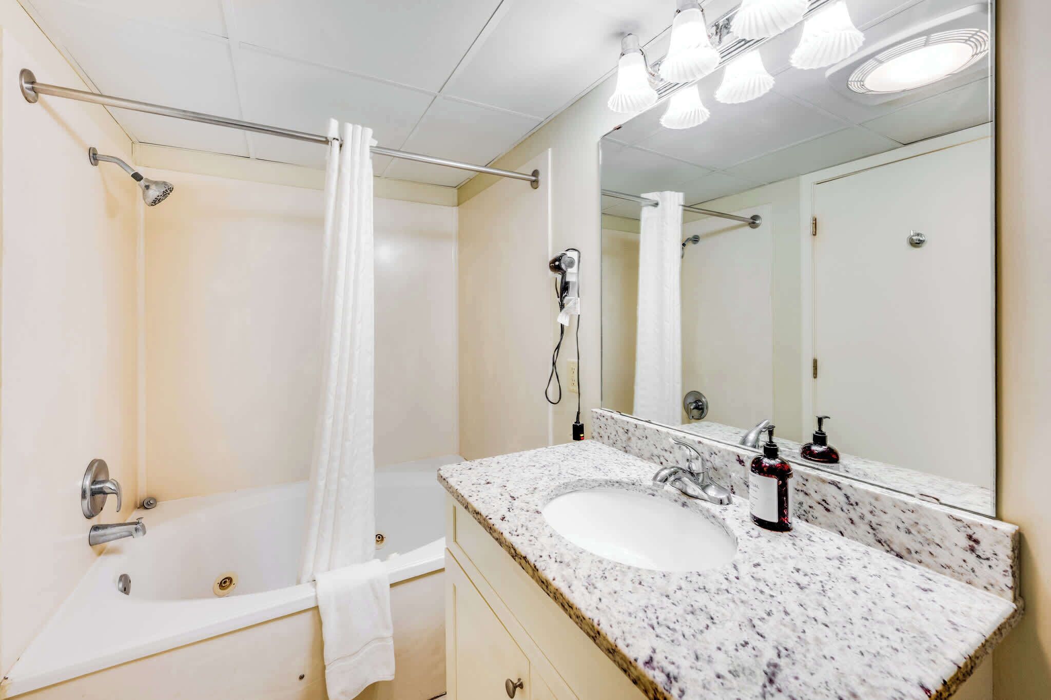 A bathroom with a bathtub, a shower, a sink with a mirror, and a towel rack.