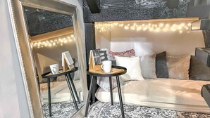 A modern bedroom with a large mirror, a round rug, and a bed with multiple pillows.