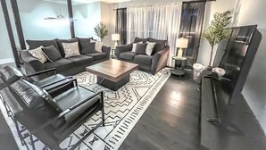 A modern living room with two sofas, a coffee table, a TV, and a patterned rug.