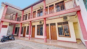 A two-story building with a balcony, wooden doors, and an air conditioning unit. - Hotel O Fj Guest House (Cileunyi)