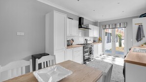 A modern kitchen with white cabinetry, a wooden table, and a view to the outside. - Super Comfortable & High Quality (Cleethorpes)