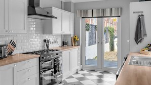 A modern kitchen with white cabinets, a gas stove, and a large window leading to a patio. - Super Comfortable & High Quality (Cleethorpes)