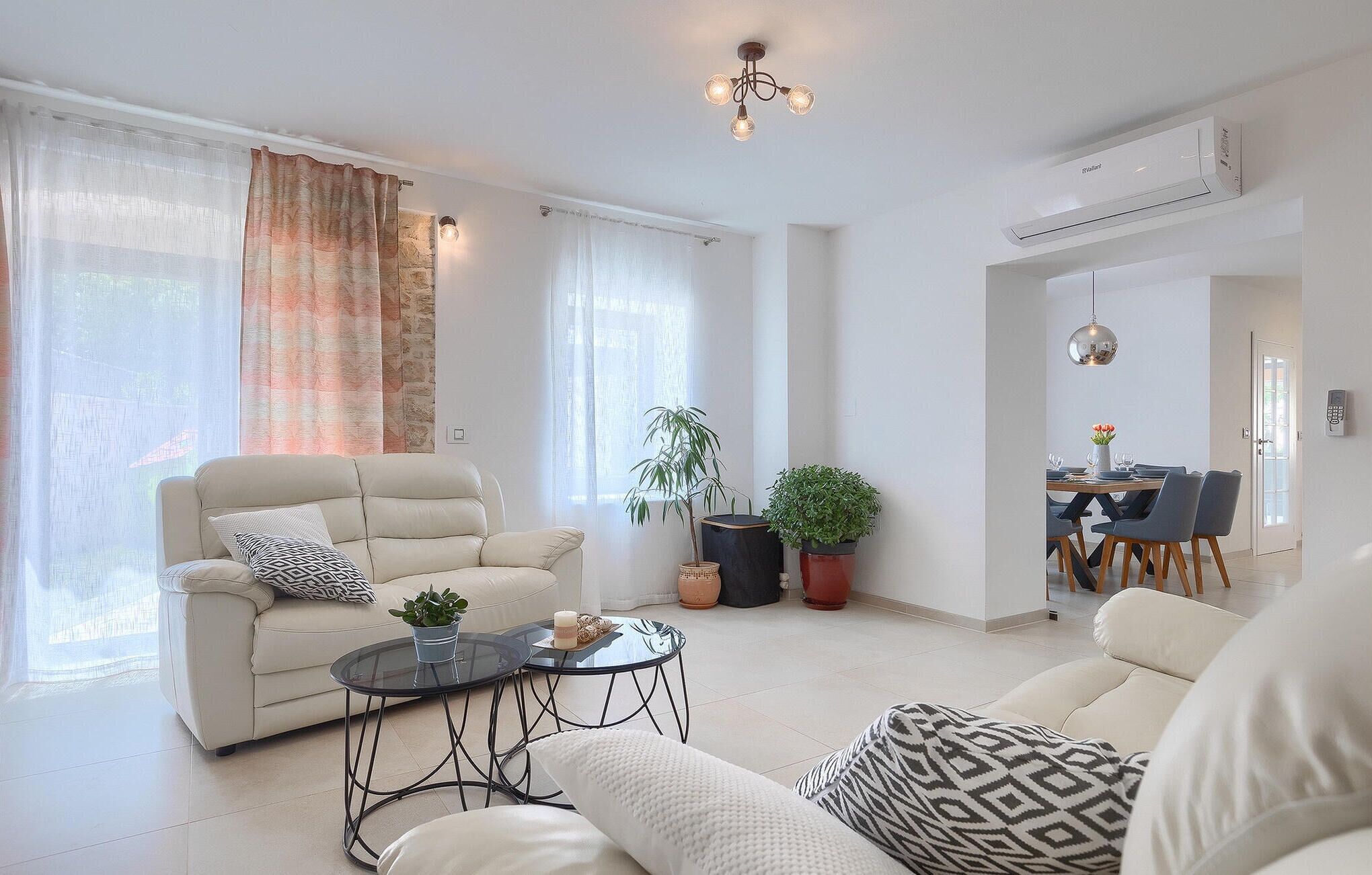 A modern living room with a sofa, a coffee table, and a dining area with chairs and a table.