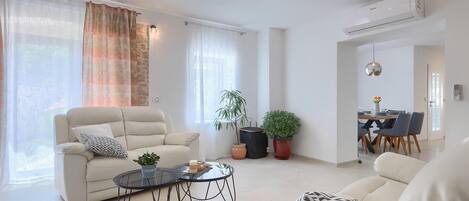 A modern living room with a sofa, a coffee table, and a dining area with chairs and a table.