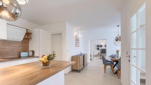 A modern kitchen with a wooden countertop, a fruit bowl, and a dining area with a table and chairs. - Awesome home in Marcana (Marcana)