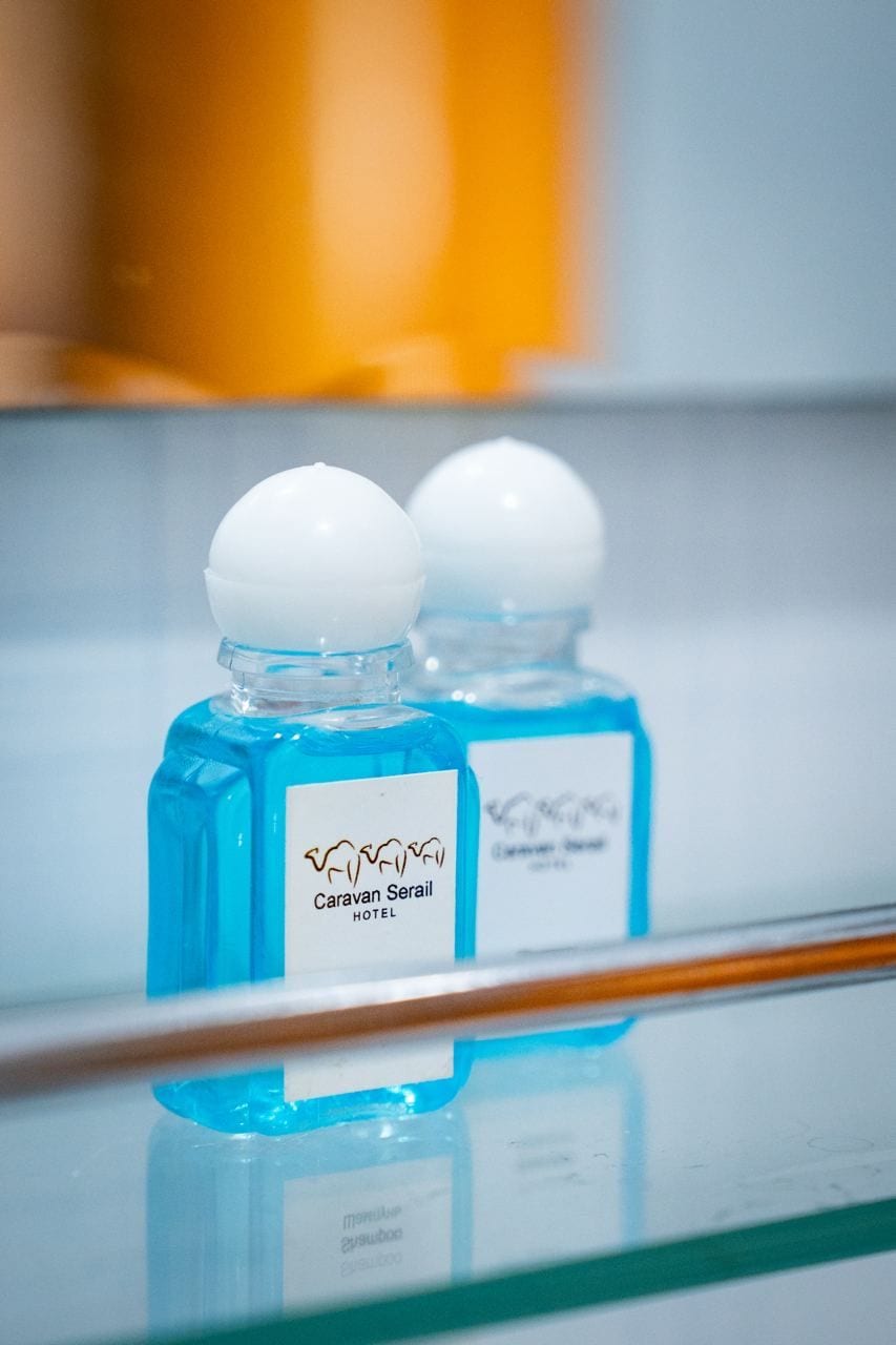 Two bottles of blue liquid with white caps on a reflective surface.