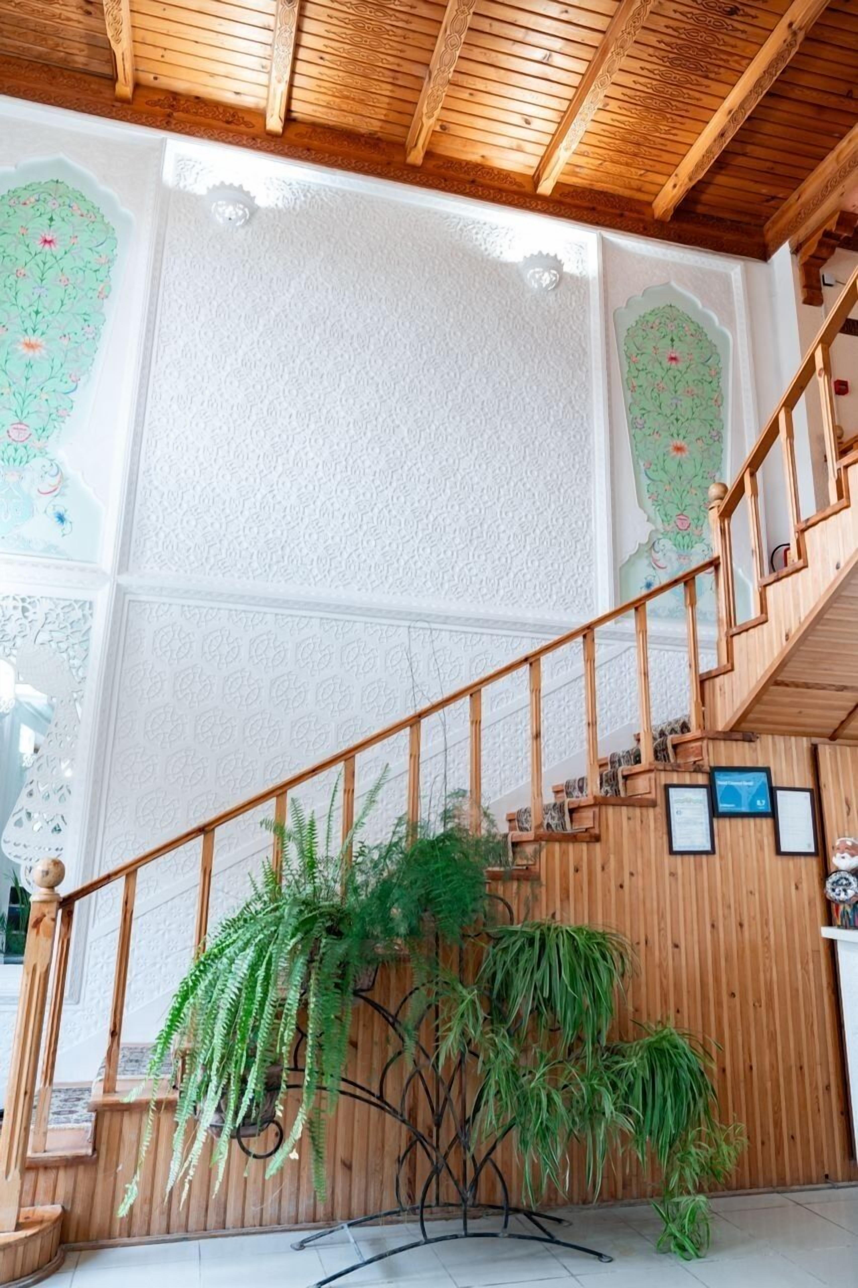 A wooden staircase with a railing, a hanging plant, and a wall with decorative panels.
