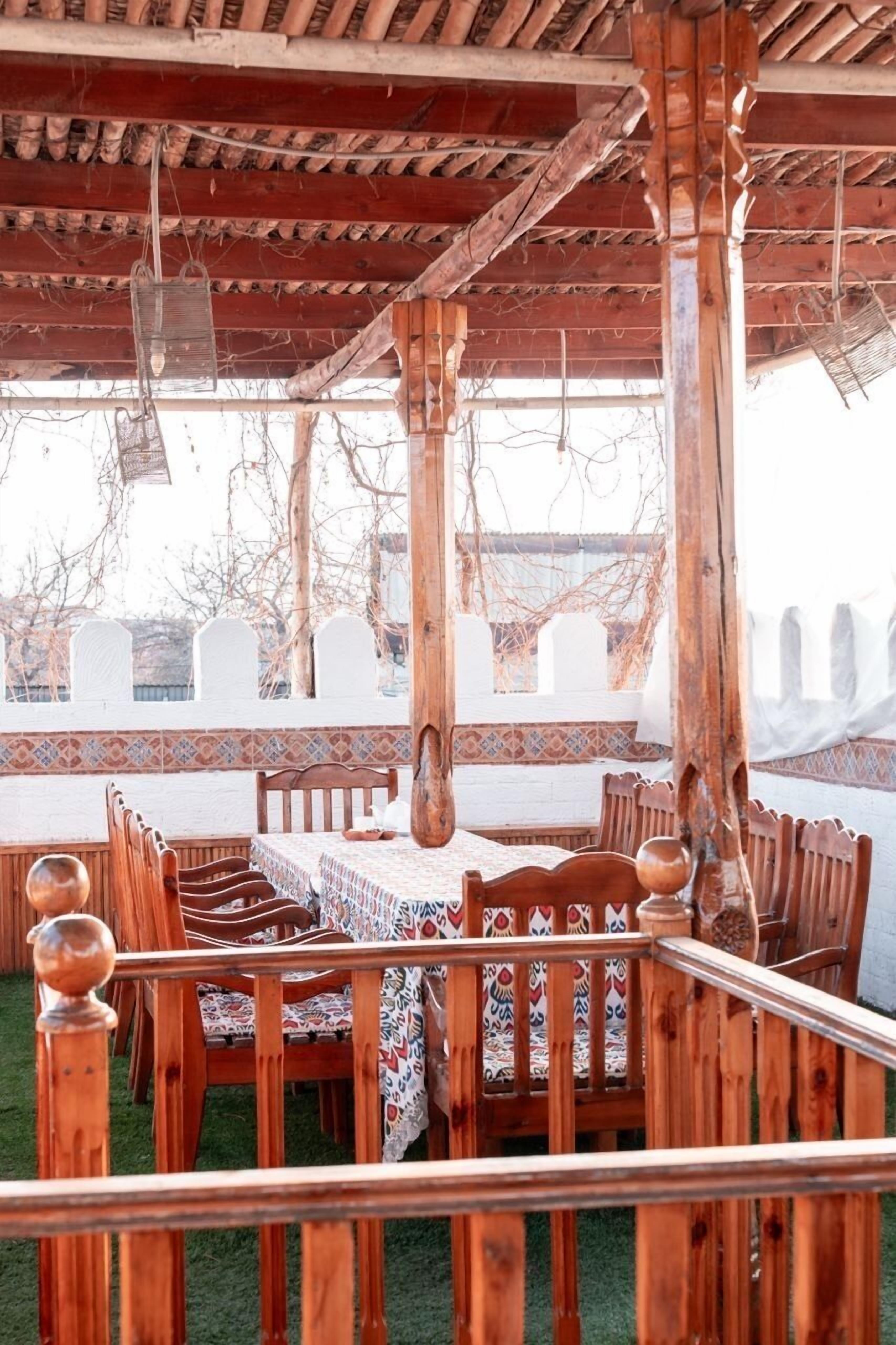 An outdoor dining area with wooden furniture and a patterned tablecloth.