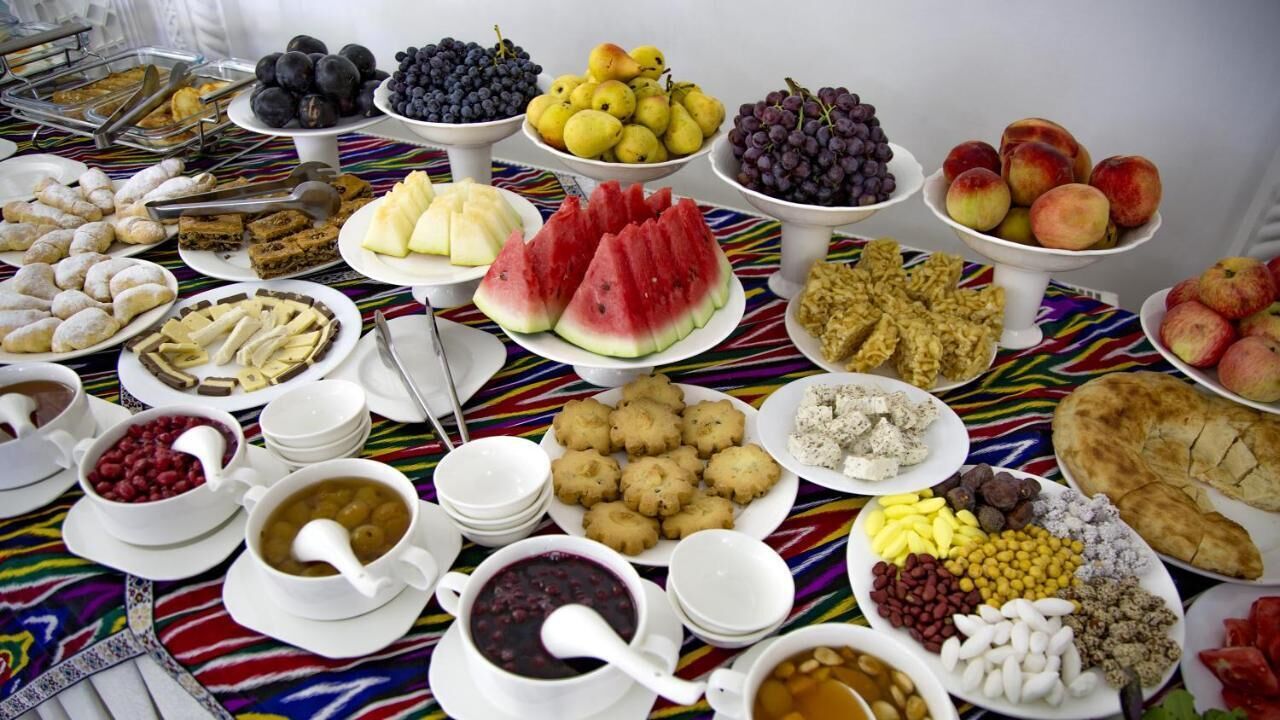 Un tavolo per buffet con diversi cibi, tra cui frutta, dolci e bevande.