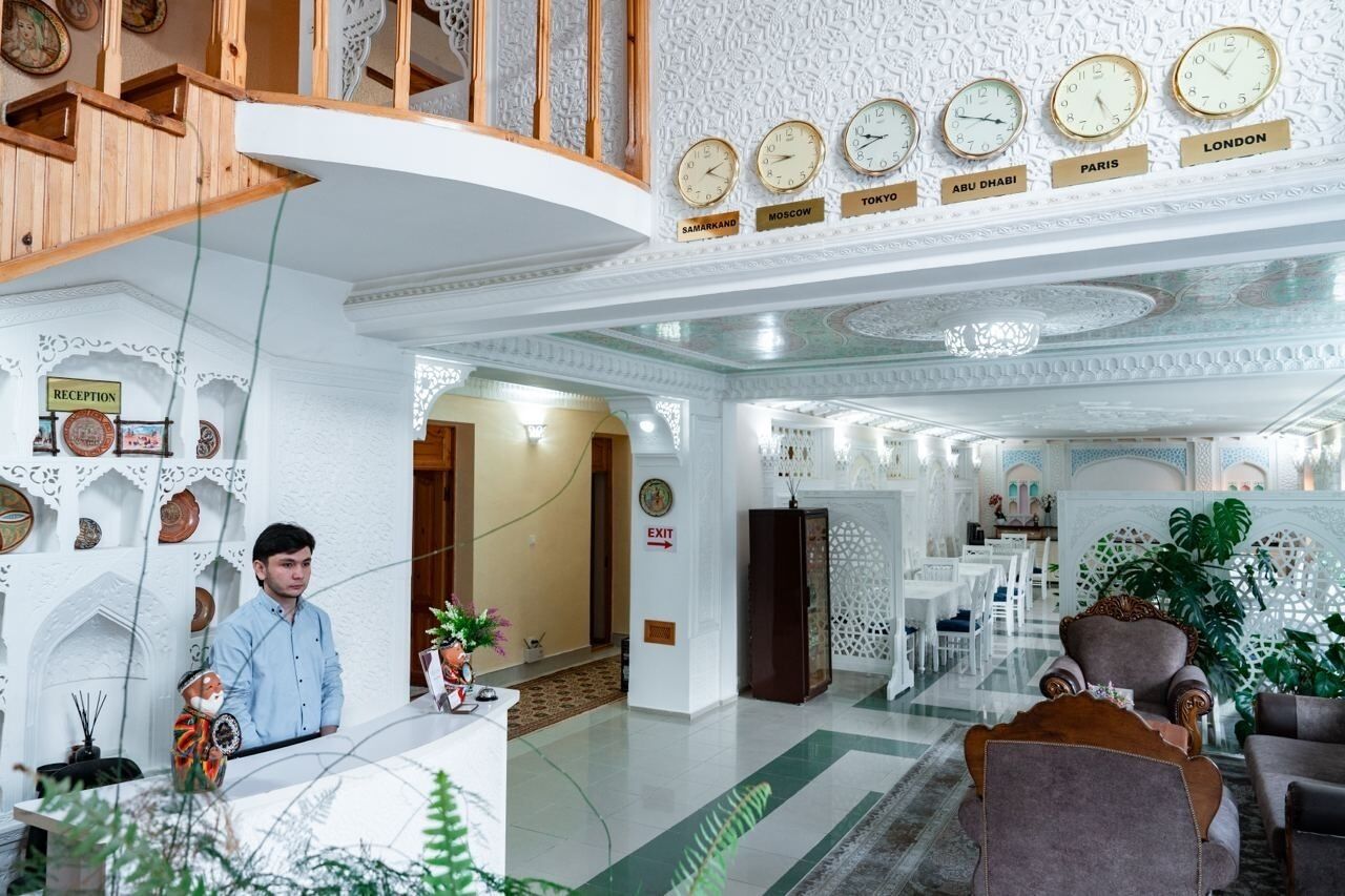 Rebedor d'hotel amb una recepció, una escala i rellotges que indiquen diferents ciutats.