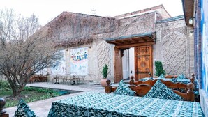 Un patio con alojamiento tipo casa de huéspedes, que incluye una puerta de madera, un muro de ladrillo con un mural y asientos exteriores.