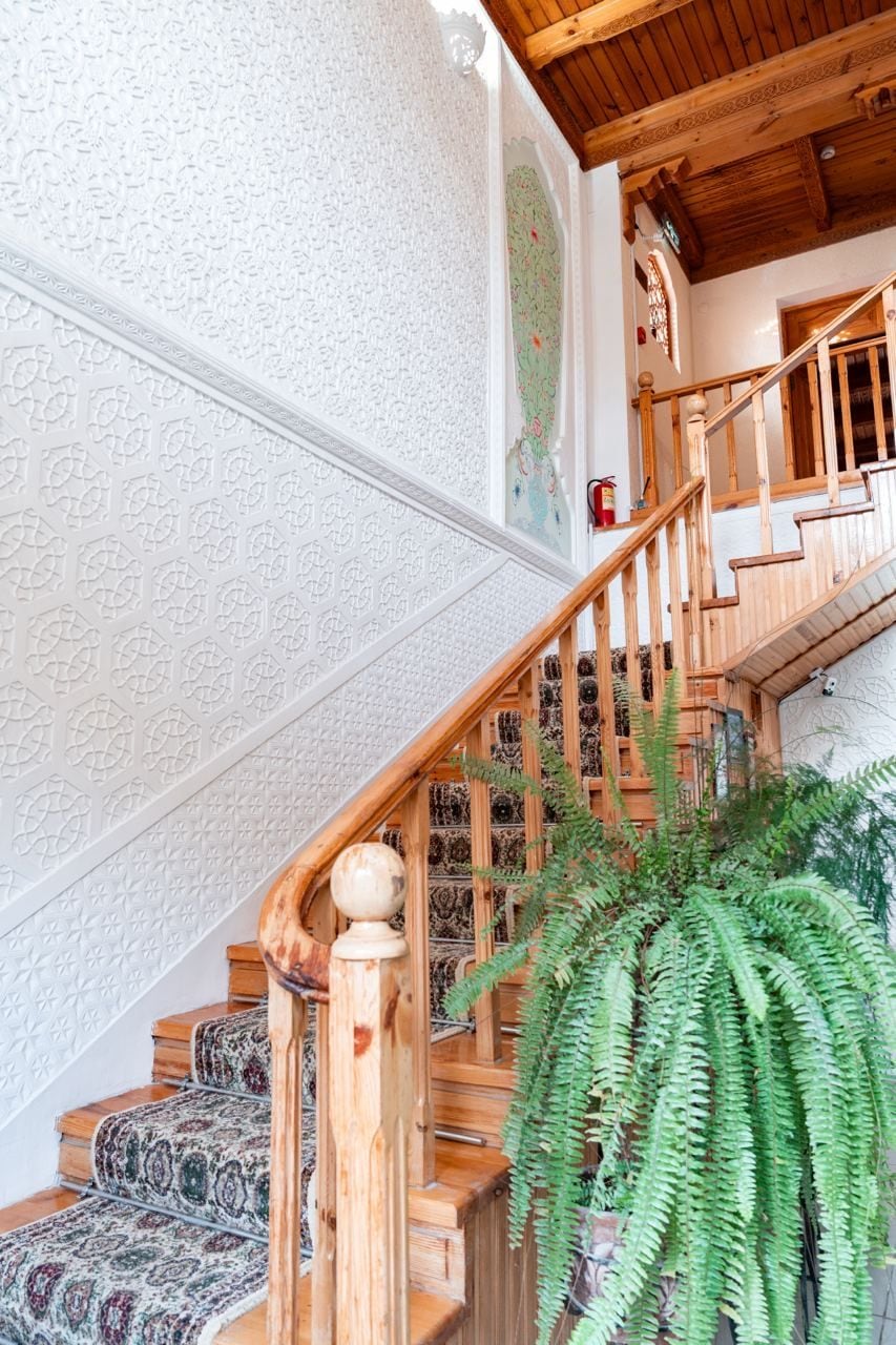 Un escalier recouvert d’une moquette à motifs et doté de rampes en bois, menant à l’étage supérieur.