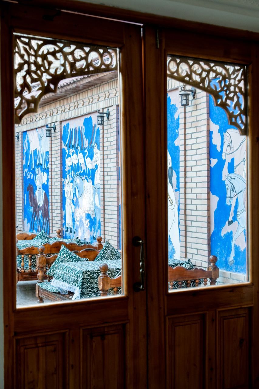 Una puerta de madera con intrincados grabados y paneles de vidrio de colores que muestran caballos y jinetes.