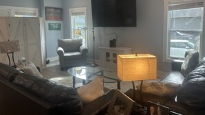Un salon équipé d’un téléviseur à écran plat, d’un ventilateur de plafond, d’un canapé, d’un fauteuil et d’une table basse.