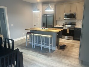 Een moderne keuken met een centraal eiland, roestvrijstalen apparatuur en licht houten vloeren.