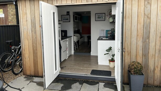 A modern kitchen with white cabinets, a black countertop, and a wooden door. - Stylish 1-bed Studio in Humberston, Cleethorpes (Grimsby)