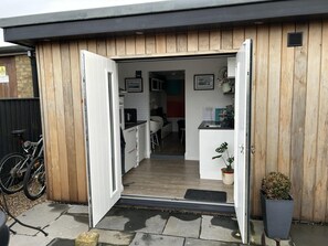 Moderni keittiö, jossa on valkoiset kaapit, musta työtaso ja puinen ovi.