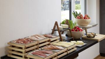 A buffet with various meats, cheeses, and vegetables.