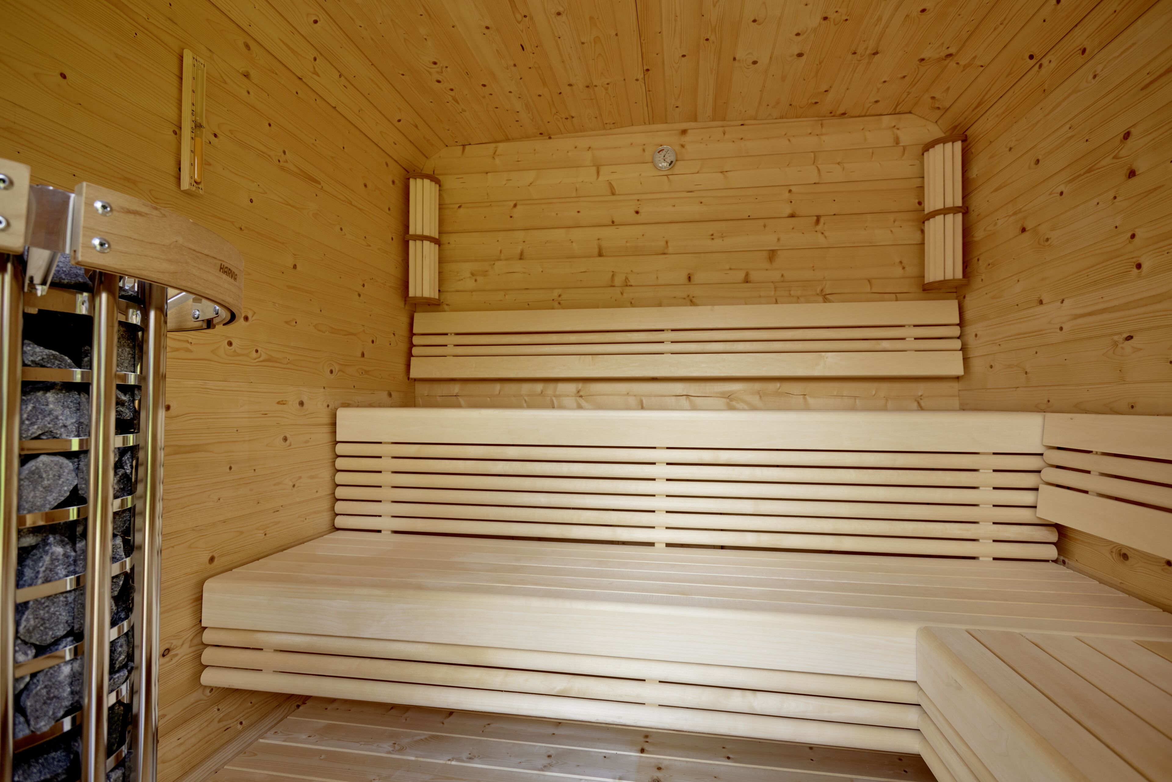 Ein Sauna-Raum mit Holzbänken und Ablagefläche aus Stein.