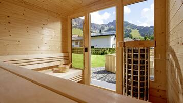 Una baita in legno con una panchina e un tavolo di legno, una porta in legno e vista su un paesaggio montano.