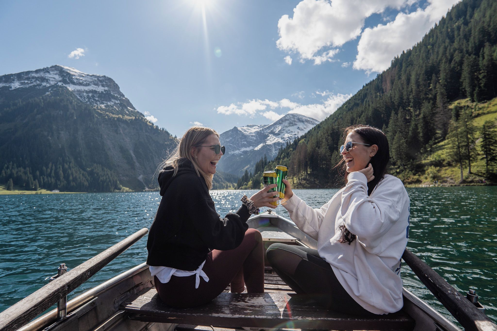 Two people on a boat with a mountainous landscape in the background.