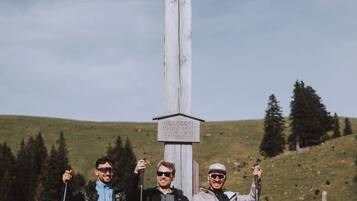 Three people sitting on a bench with a wooden cross in the background.
