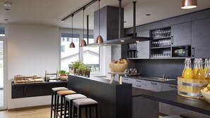 Una cocina moderna con una isla central, taburetes de bar y un frutero.