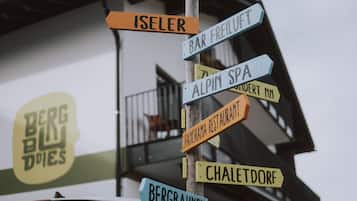 Un cartel con varias indicaciones direccionales que señalan a diferentes lugares como 'Iseler', 'Bar Freilift', 'Alpin Spa', 'Chaletdorf' y 'Bergbahnen'.