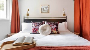 A neatly made bed with a book, pillows, and a bedside table.