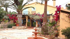 Une cour avec une fontaine, des plantes en pot et un bâtiment doté de balcons.