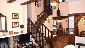 Un intérieur chaleureux avec une cheminée, un escalier en bois et un coin repas.