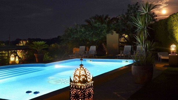 Une piscine avec des chaises longues et une lanterne décorative.