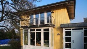 Ein zweistöckiges Haus mit Balkon, großen Fenstern und einer Garage.