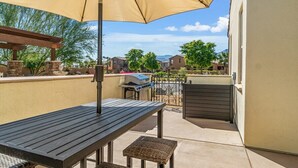 An outdoor patio with a table, an umbrella, and a grill. - Verdant Views & Amenities Near PGA West Golf (La Quinta)