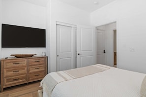 Une chambre à coucher avec un lit, une commode en bois et deux portes blanches.