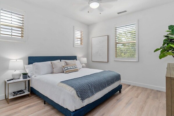 A bedroom with a bed, bedside tables, a ceiling fan, and a window with blinds.