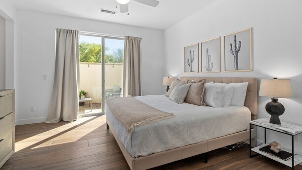 A bedroom with a bed, a ceiling fan, a nightstand with a lamp, and a window with curtains. - Verdant Views & Amenities Near PGA West Golf (La Quinta)