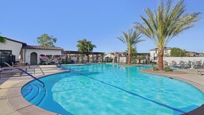 A swimming pool with clear blue water, surrounded by lounge chairs and palm trees. - Verdant Views & Amenities Near PGA West Golf (La Quinta)
