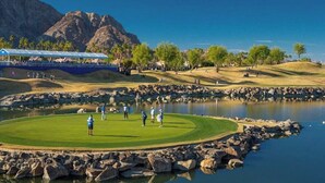 A golf course with a pond, a rocky shoreline, and a mountainous backdrop. - Verdant Views & Amenities Near PGA West Golf (La Quinta)