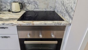 A kitchen with a Bosch induction cooktop, a built-in oven, and a coffee maker on a marble countertop. - Casas da Oliveira - Galega (Setúbal)