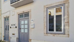 A building with two doors, numbered 21 and 23, and a window with a metal frame. - Casas da Oliveira - Galega (Setúbal)