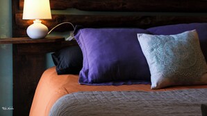 A bed with a wooden headboard, a bedside lamp, and multiple pillows. - Casa Rural Hitohouse Bed&climb (Albarracín)